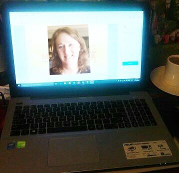 "A smiling woman's face visible on a laptop screen during a virtual interaction."