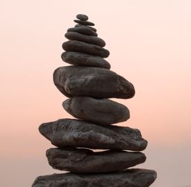 s"A stack of balanced pebbles set against a serene sunset backdrop, evoking a sense of tranquility."