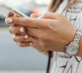 "A woman holding a mobile phone with both hands, appearing to read a message."