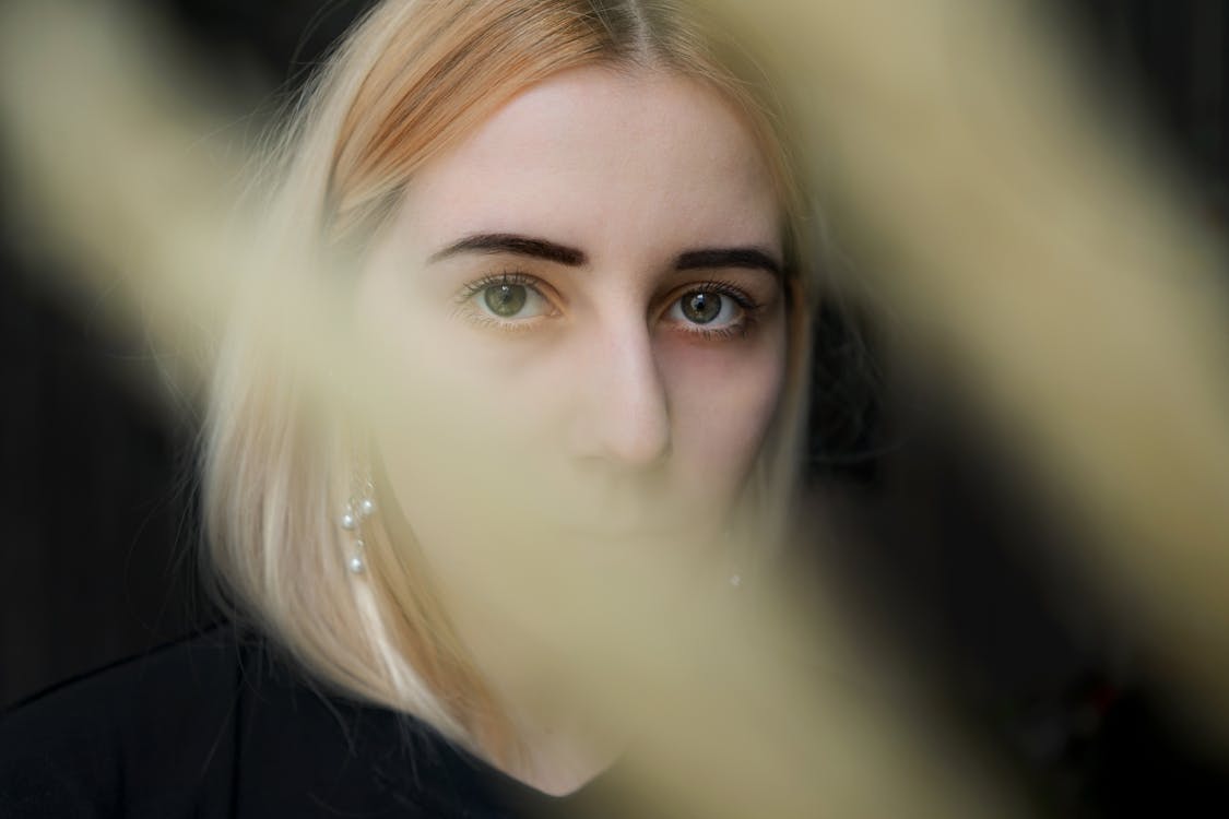 "A teenage female  peering through a hazy or blurred environment, suggesting intro-spection or curiosity."