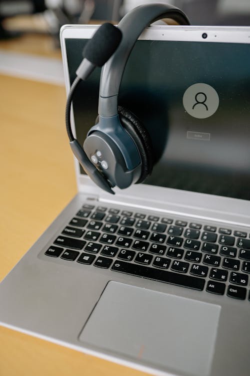 "An open laptop with a pair of headphones draped over the screen, suggesting an online learning or meeting setup."
