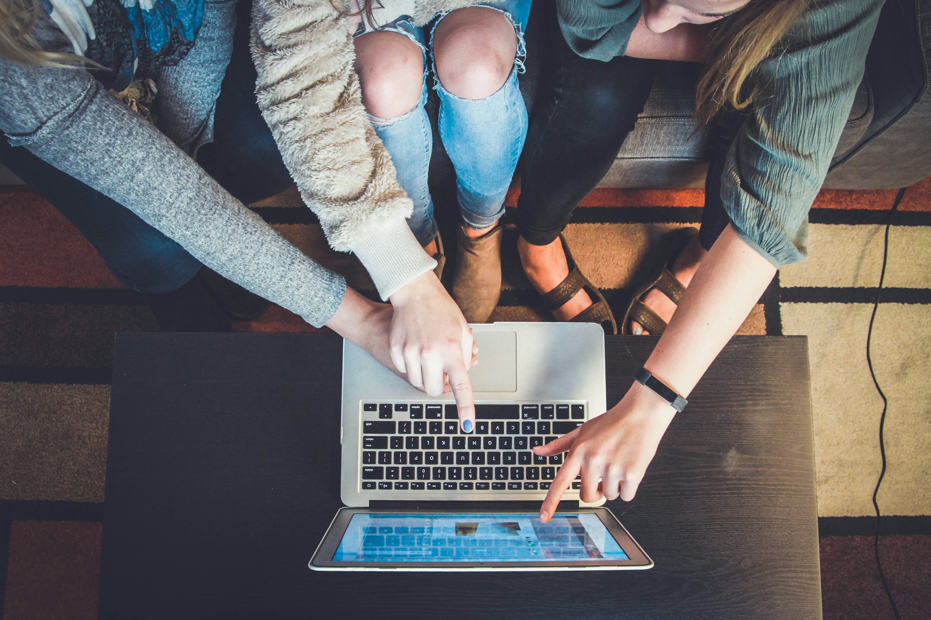The hands of three people on a laptop keyboard, engaging in an activity